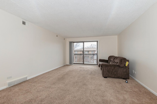 sitting room with light colored carpet and a textured ceiling