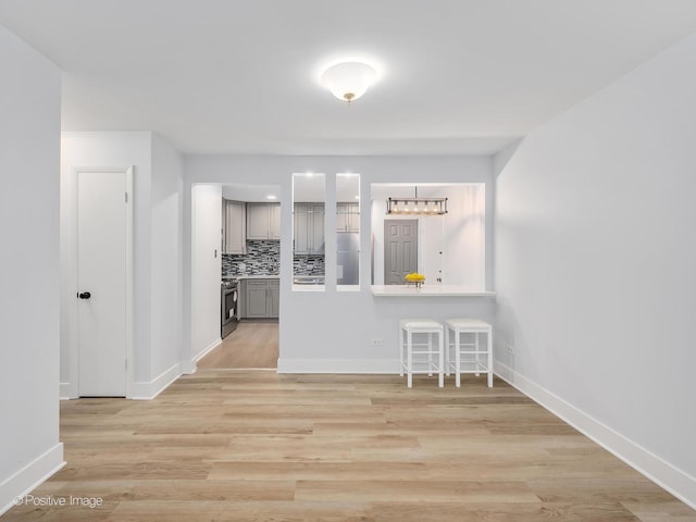 kitchen with backsplash, light hardwood / wood-style floors, stainless steel range with electric cooktop, and gray cabinetry