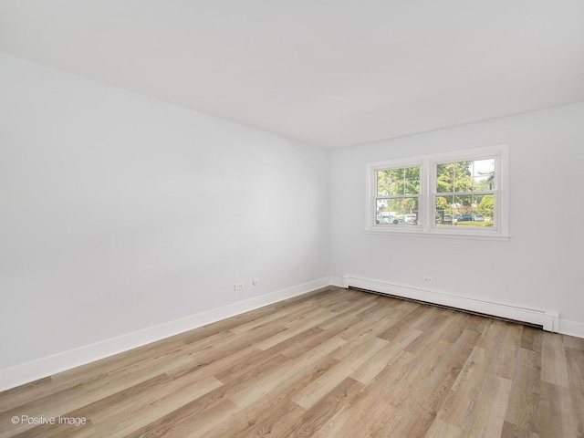 spare room with baseboard heating and light wood-type flooring