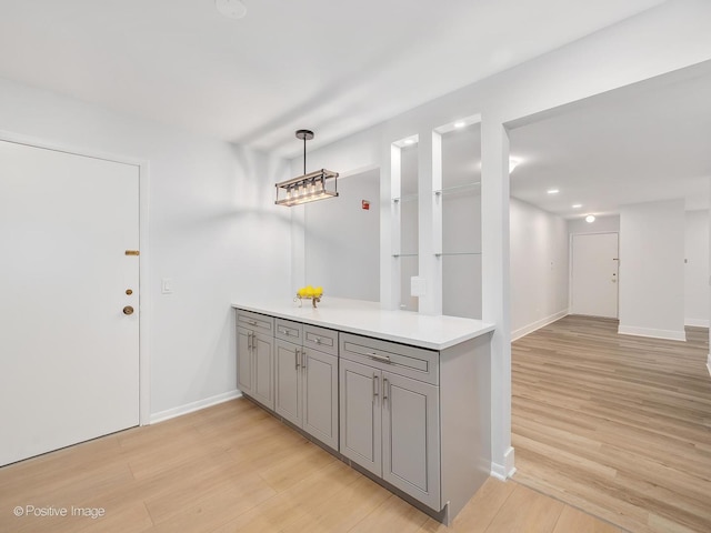 kitchen with gray cabinets, light hardwood / wood-style floors, and decorative light fixtures