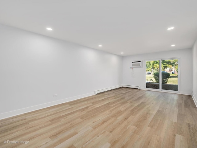 spare room with light hardwood / wood-style floors, an AC wall unit, and baseboard heating