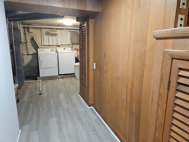 laundry room with light hardwood / wood-style floors, wood walls, and washing machine and dryer