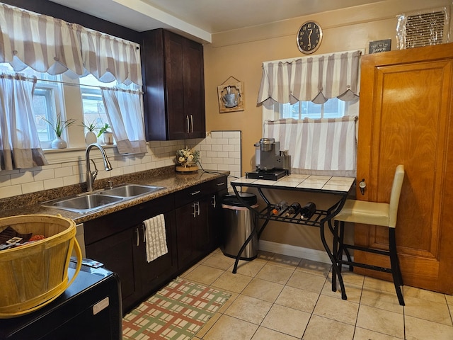 kitchen with backsplash, sink, dark brown cabinetry, and light tile patterned flooring