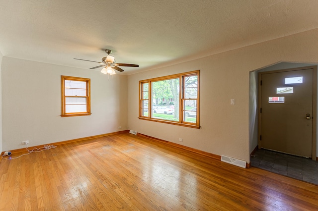 unfurnished room with light hardwood / wood-style floors, a textured ceiling, and ceiling fan