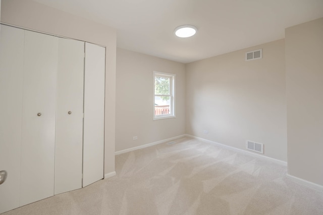 unfurnished bedroom featuring light colored carpet and a closet