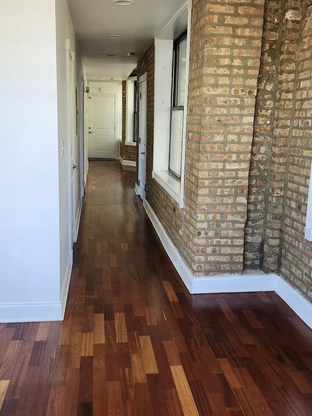 6410 N Hoyne Ave Unit 3E, Chicago, IL 60645 - corridor featuring baseboards, brick wall, and wood finished floors