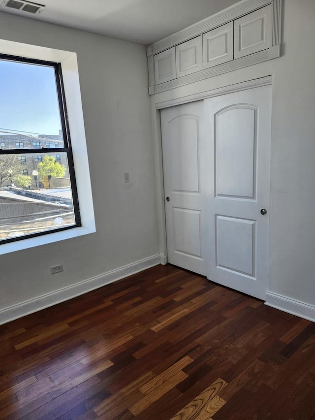 6410 N Hoyne Ave Unit 3E, Chicago, IL 60645 - unfurnished bedroom with dark wood-style flooring, baseboards, and a closet