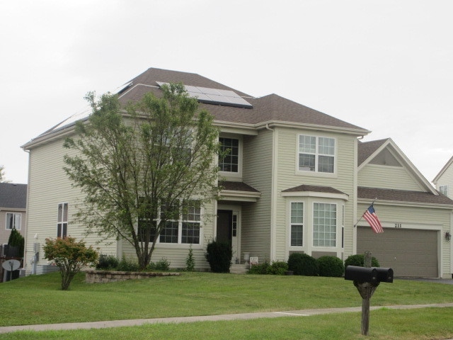 view of front of property featuring solar panels, a front yard, and a garage