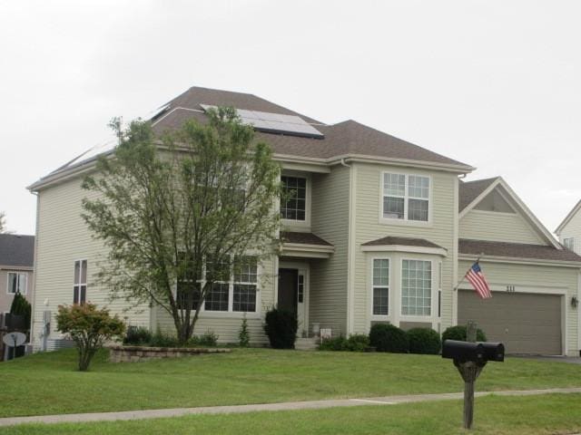 view of front facade with a garage, roof mounted solar panels, and a front yard
