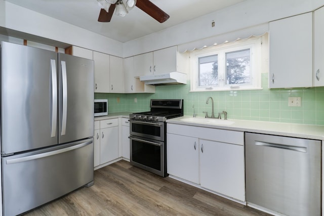 kitchen with white cabinets, appliances with stainless steel finishes, wood-type flooring, and sink