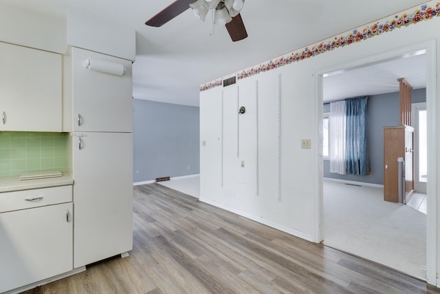 kitchen featuring white cabinets, light wood-type flooring, tasteful backsplash, and ceiling fan