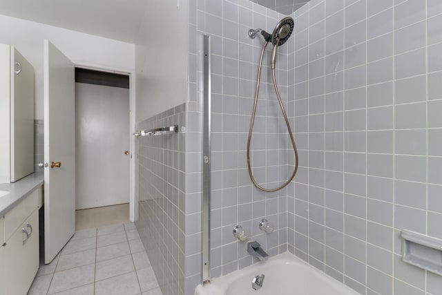 bathroom with tile patterned flooring, vanity, tiled shower / bath combo, and tile walls