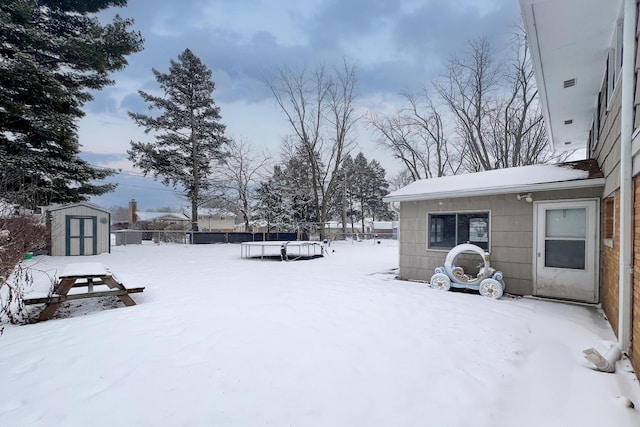 yard layered in snow featuring a shed