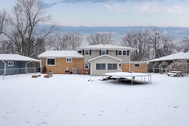 snow covered house featuring central AC unit and a trampoline