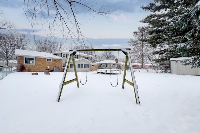 yard layered in snow featuring a playground and cooling unit