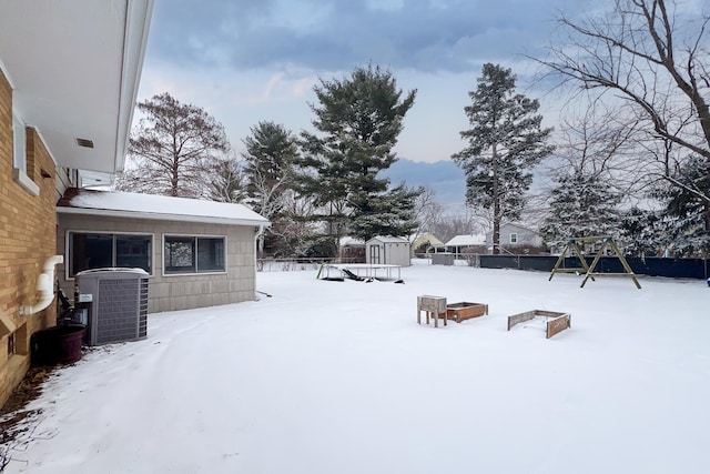 snowy yard featuring a storage shed and central air condition unit