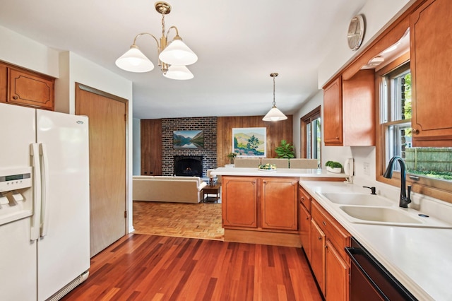 kitchen with dishwasher, white fridge with ice dispenser, hanging light fixtures, a brick fireplace, and a chandelier