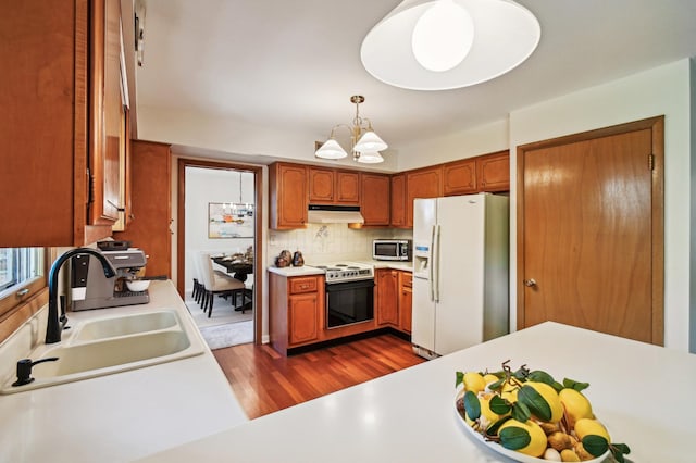 kitchen with decorative backsplash, appliances with stainless steel finishes, sink, pendant lighting, and a notable chandelier