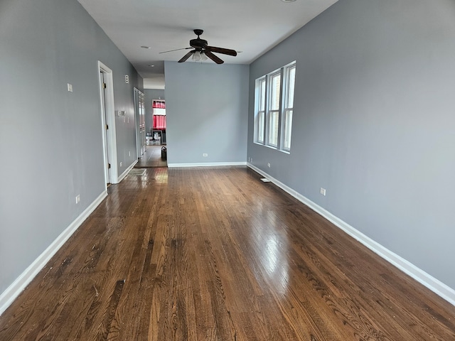 unfurnished living room featuring dark wood-type flooring and ceiling fan