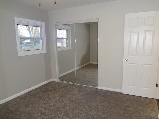 unfurnished bedroom with dark carpet and a closet