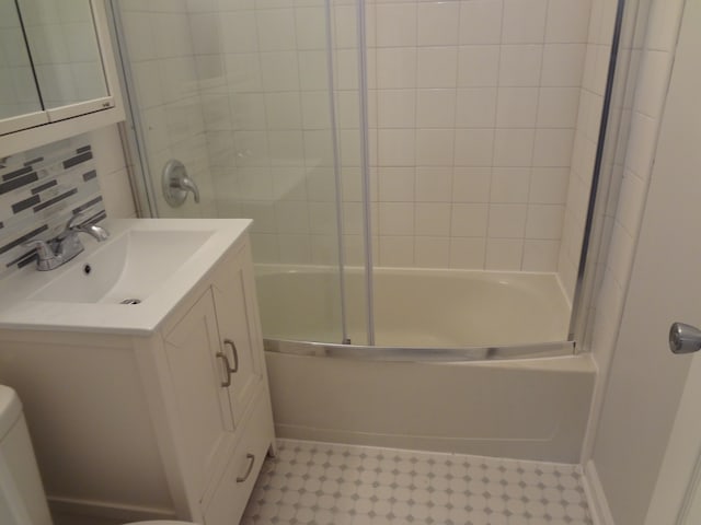 full bathroom with vanity, combined bath / shower with glass door, toilet, and backsplash