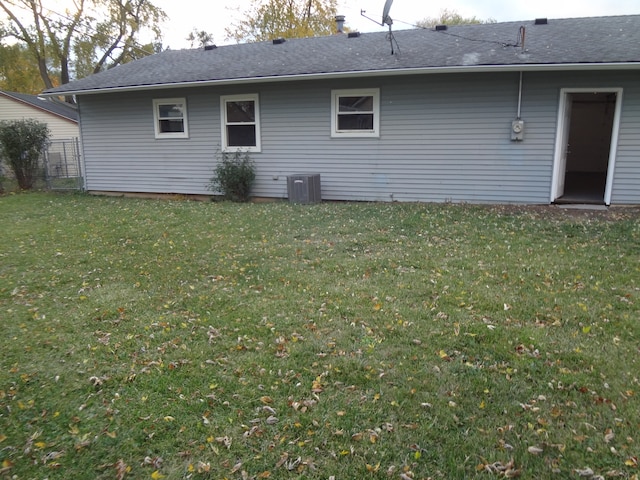 rear view of property with central air condition unit and a yard