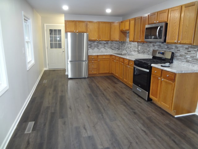 kitchen with dark wood-type flooring, appliances with stainless steel finishes, sink, and decorative backsplash