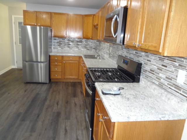 kitchen featuring backsplash, sink, appliances with stainless steel finishes, light stone counters, and dark hardwood / wood-style flooring