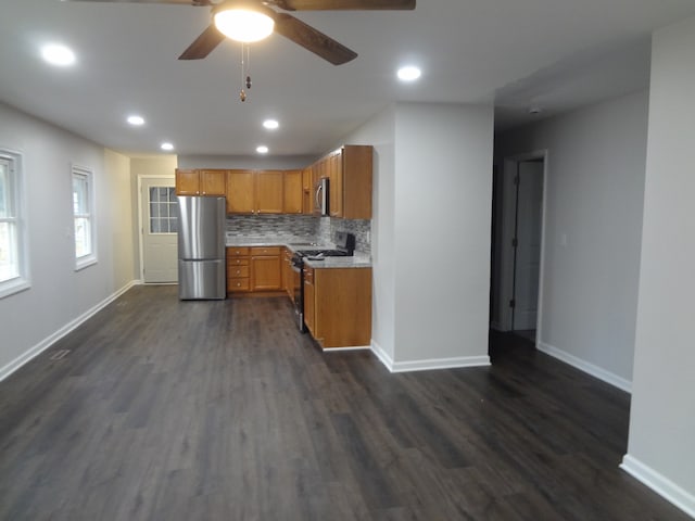 kitchen with dark wood-type flooring, appliances with stainless steel finishes, ceiling fan, and tasteful backsplash