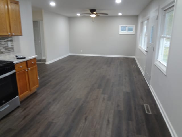 kitchen featuring decorative backsplash, ceiling fan, stainless steel range with electric cooktop, and dark hardwood / wood-style flooring