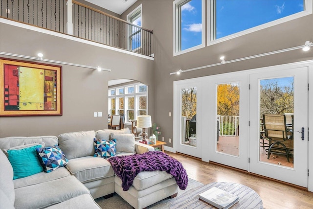 living room with light wood-type flooring and a towering ceiling