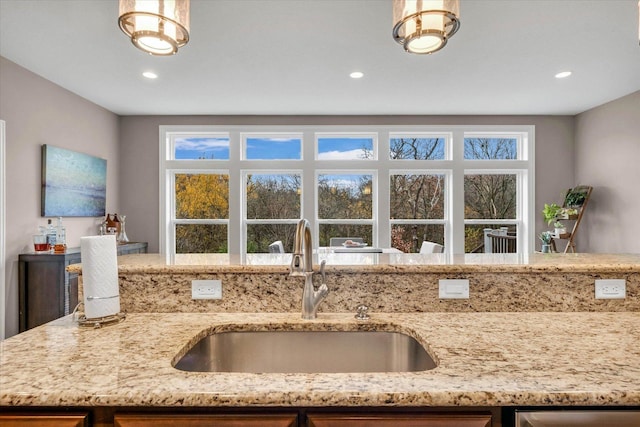 kitchen with light stone countertops, plenty of natural light, and sink