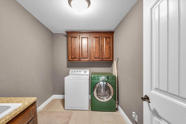 laundry room featuring cabinets, a textured ceiling, and washing machine and clothes dryer