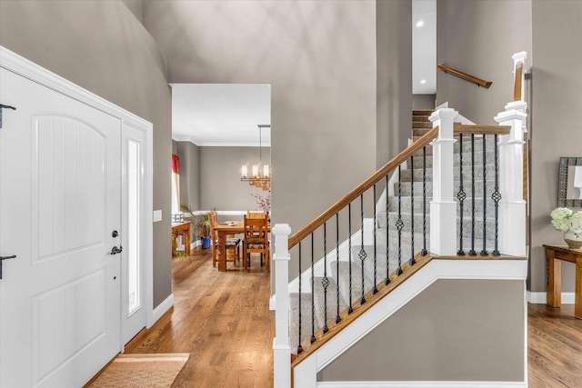 foyer with a notable chandelier, light wood-type flooring, and ornamental molding