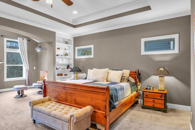 bedroom with ceiling fan, light colored carpet, ornamental molding, and a tray ceiling