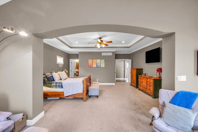 carpeted bedroom with a raised ceiling, ceiling fan, and crown molding