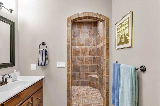 bathroom featuring tiled shower and vanity