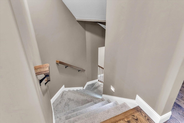 stairway featuring carpet floors and a textured ceiling