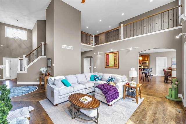 living room with wood-type flooring, a high ceiling, and an inviting chandelier