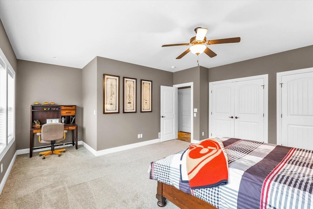 bedroom featuring multiple closets, ceiling fan, and light carpet