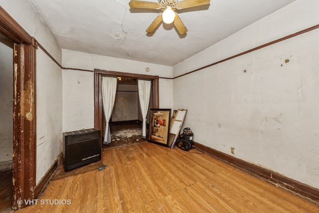 spare room with heating unit, light wood-type flooring, and ceiling fan