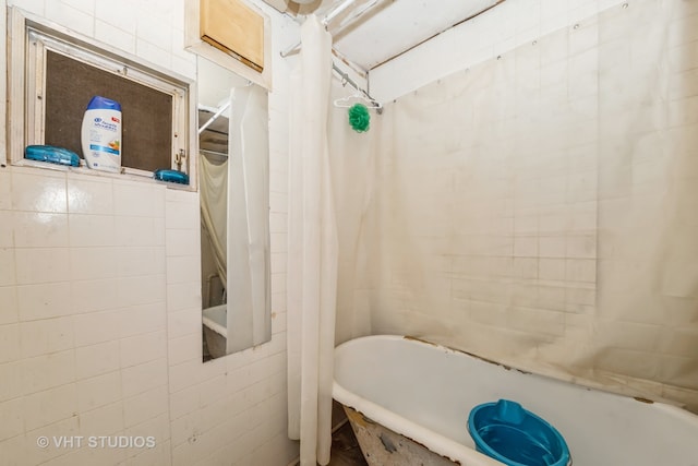 bathroom with shower / bath combo with shower curtain and tile walls