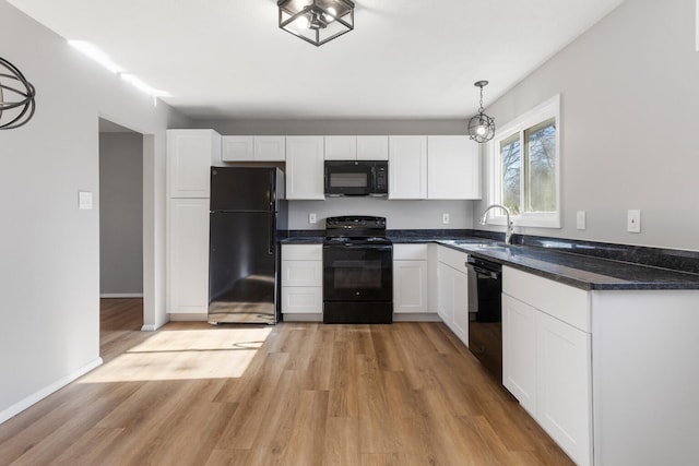 kitchen featuring black appliances, sink, hanging light fixtures, light wood-type flooring, and white cabinetry