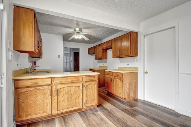 kitchen featuring kitchen peninsula, ceiling fan, a textured ceiling, hardwood / wood-style flooring, and sink