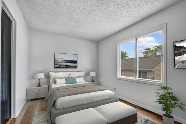 bedroom with hardwood / wood-style floors and a textured ceiling