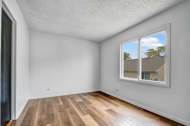 unfurnished room with a textured ceiling and light wood-type flooring