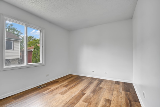 spare room with a textured ceiling and light wood-type flooring