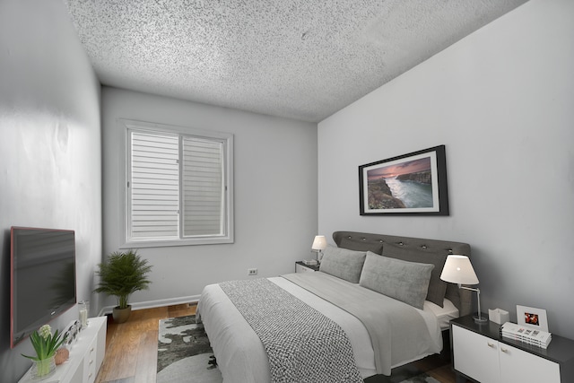 bedroom featuring a textured ceiling and dark hardwood / wood-style flooring