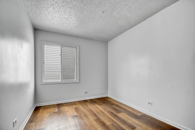 spare room featuring a textured ceiling and hardwood / wood-style flooring