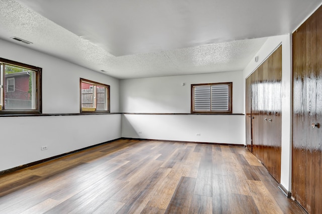 unfurnished room with a textured ceiling and hardwood / wood-style flooring